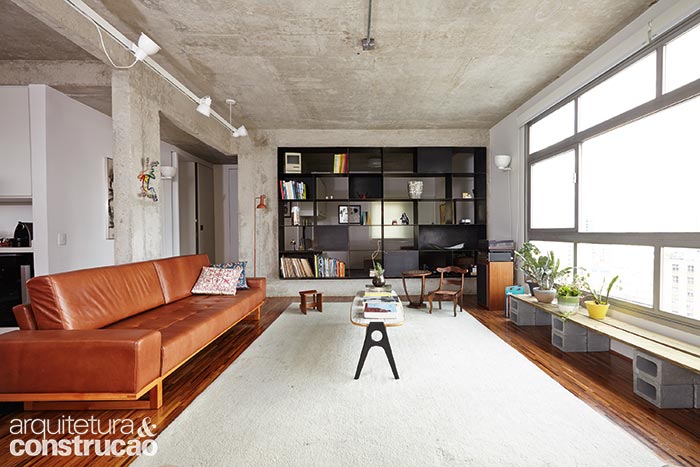 Descoberta na demolição, a viga invertida (no piso) foi assumida pelos arquitetos Flávia Torres, Pedro Freire e a equipe do Sub Estúdio, que encaixou uma estante em meio aos elementos estruturais. De ferro, com 40 cm de profundidade e soldada no local por Samoel Dutra, ela se abre para a sala e para o home theater.