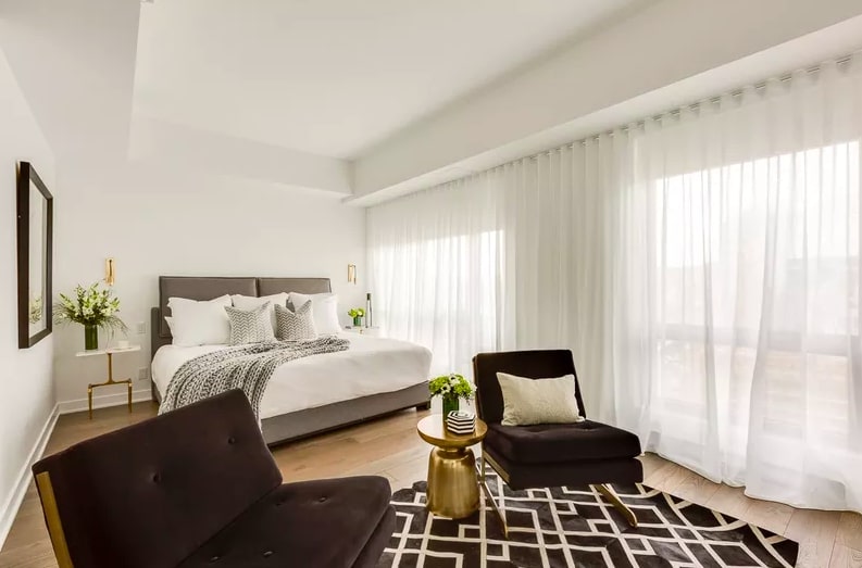 Dê uma suavidade visual e literal ao seu quarto preto e branco com a ajuda de cortinas transparentes e esvoaçantes. Este projeto utiliza cortinas de parede a parede, o que torna o quarto luminoso e arejado, apesar da adição de cores escuras