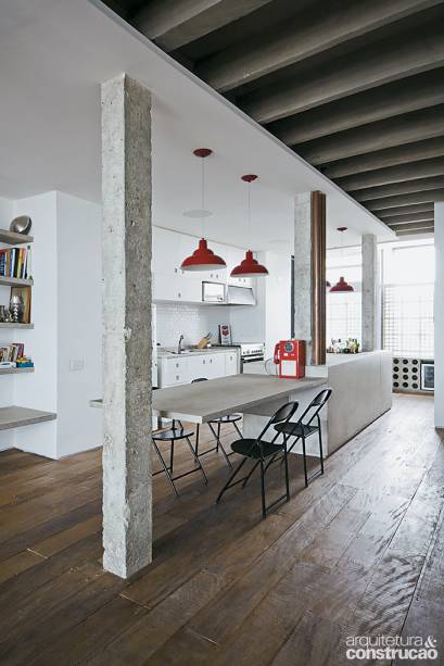 Apesar das poucas paredes, há lugar certo para todo tipo de objeto, na sala e na cozinha: acomodados em nichos de gesso (à dir. na foto) feitos pela Pórtico ou em bancadas e prateleiras de concreto armado (lisinho e com apenas 5 cm de espessura, especialidade da Onofre Móveis). Os pendentes são de segunda mão. No piso, assoalho de peroba de demolição da Pau-Pau Pisos de Madeira.