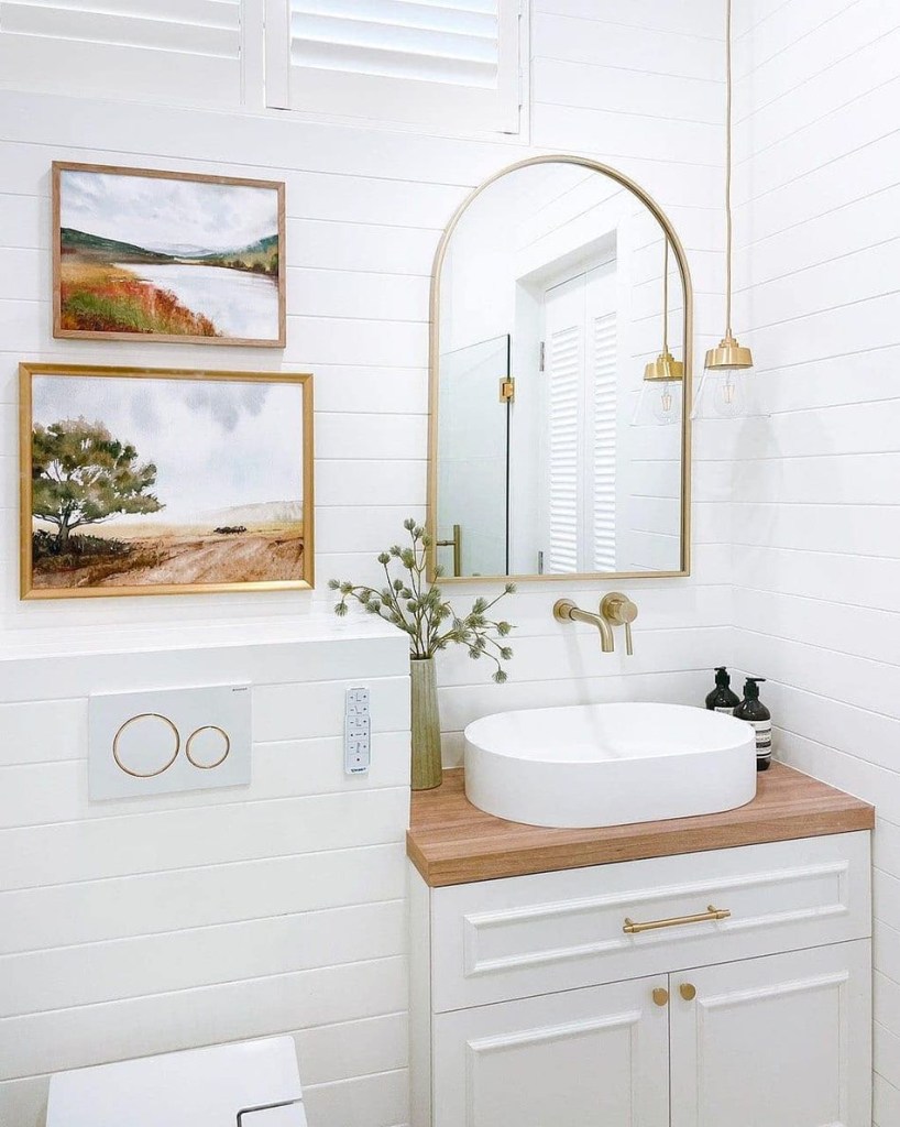 Banheiro com paredes em azulejo branco e detalhes dourados