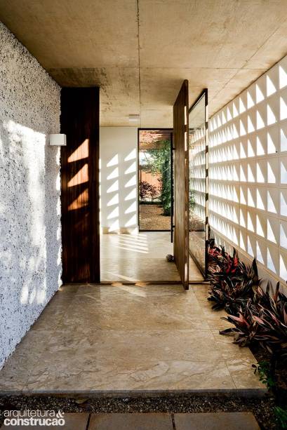 Com a intenção de barrar o sol poente que incide deste lado da casa brasiliense, o escritório cbr arquitetura ergueu na fachada uma parede de 3 x 14 m com elementos vazados de concreto (Premoldado Brasil) pintados de branco. Na entrada, um vidro separa o estar – recurso dispensado na sala de jantar, ao fundo, junto ao jardim com pergolado.