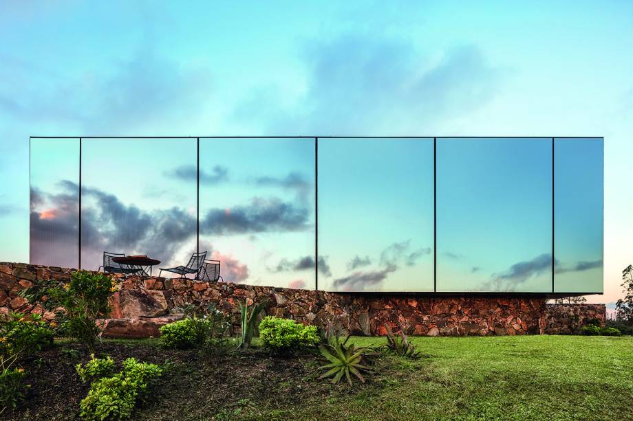 SAC, MALDONADO, URUGUAI, 2018: No horizonte de vinhedos, serra e pradarias do interior do Uruguai, a fachada deste refúgio intriga o olhar ao se camuflar na natureza. “Desejávamos a relação enigmática proporcionada pelo vidro espelhado. A transparência amplia o espaço interior da construção e ao mesmo tempo cria uma imagem exterior quase mágica, mimetizando a paisagem”, diz Luciano. O módulo pré-fabricado é uma das treze unidades de um projeto maior, o Sacromonte Landscape Hotel, ainda não inaugurado.