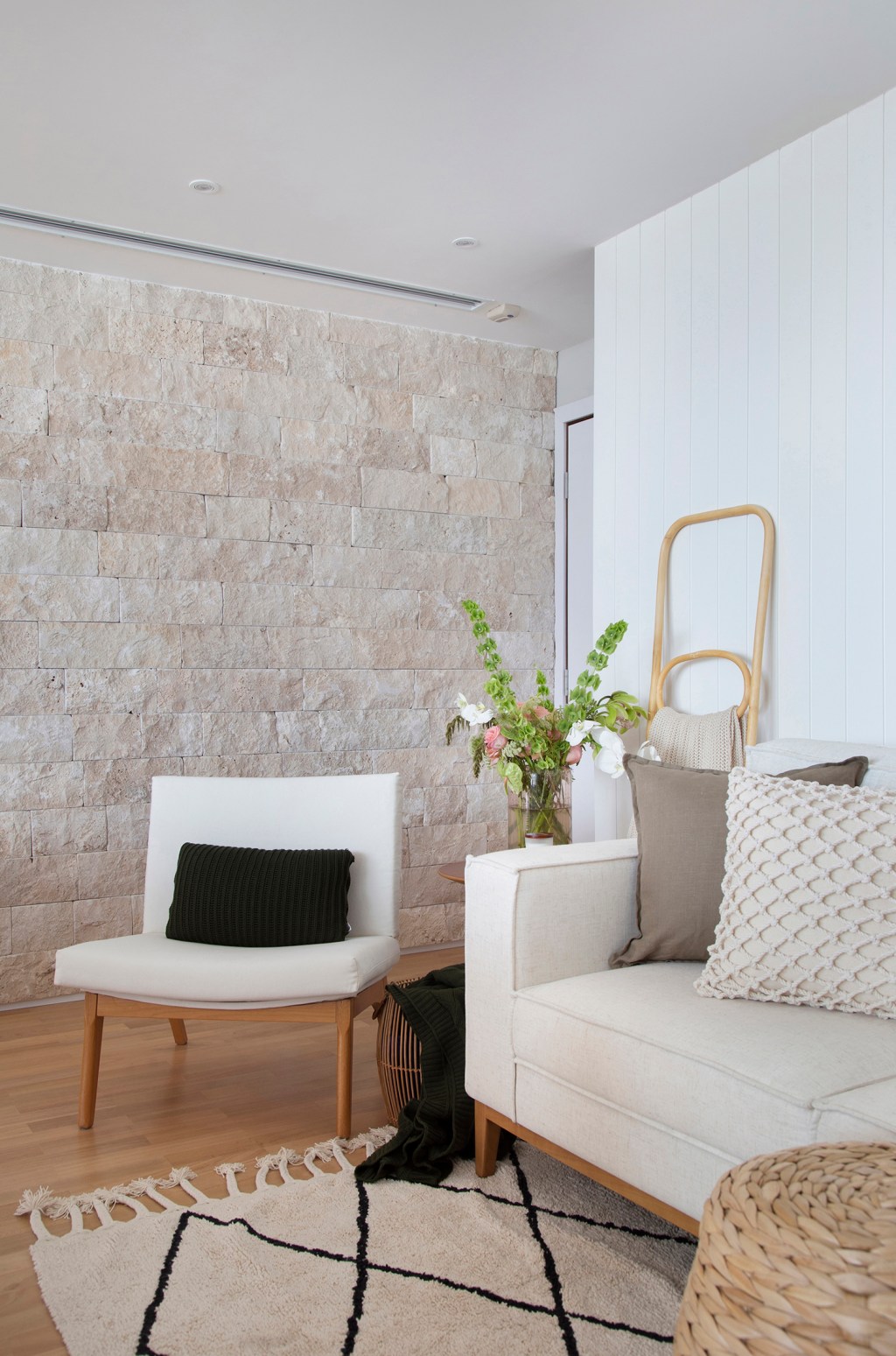 Estilo comfy; sala de estar; sofá off white; poltrona branca; parede de pedra; tapete