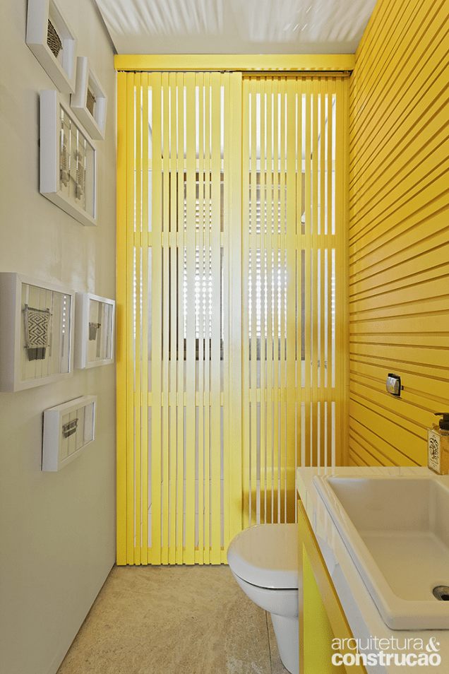 A divisória que separa o lavabo da área do chuveiro combina com as cores da parede e da bancada
