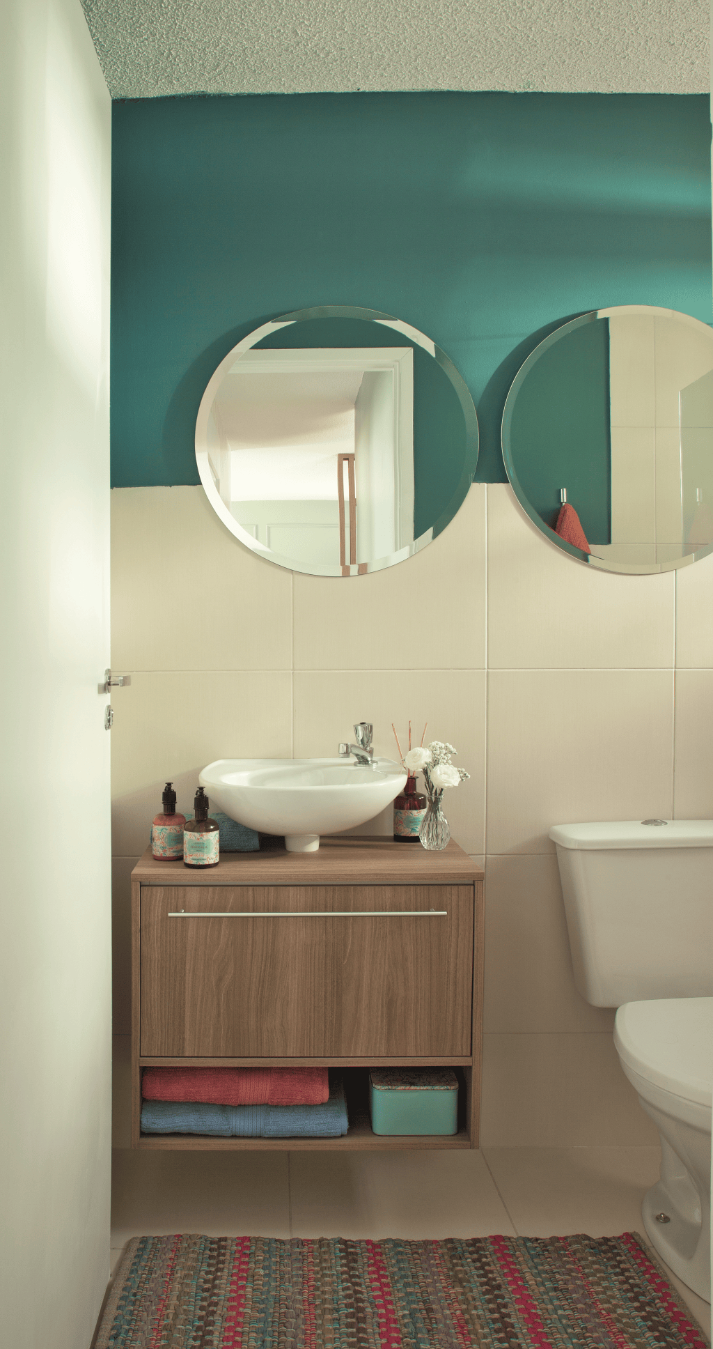 Neutro, o &uacute;nico banheiro do ap&ecirc; n&atilde;o precisou de muito para ficar charmoso: bastaram algumas pinceladas de azul, um gabinete sob medida e espelhos redondos. Projeto da designer de interiores Maria Veridiana Leoni, da M2House, e do arquiteto Kennory Weston, KW Arquitetura.