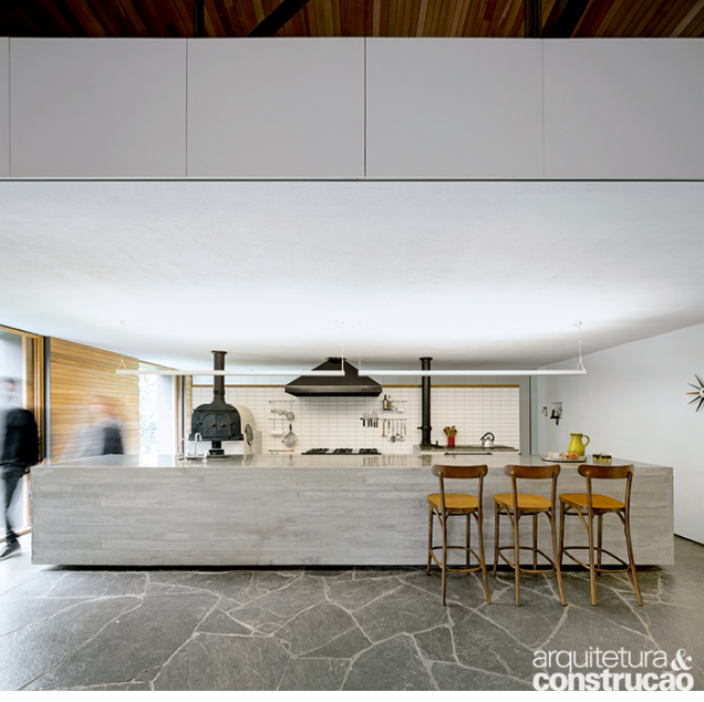 A ilha (0,93 x 1 x 5,85 m) com tampo de rocha basaltite confere tom contemporâneo à proposta do Studio MK27, realizada com o trabalho dos arquitetos Marcio Kogan e Maria Cristina Motta. Ao fundo, na parede revestida de azulejos de 7,5 x 15 cm (ref. Metro Bisotado, da Cerâmica Antigua), distribuem- -se os fornos de pizza e à lenha, além do fogão industrial entre eles. O piso é de ardósia cinza. Projeto de interiores assinado por Diana Radomysler. A ilha (0,93 x 1 x 5,85 m) com tampo de rocha basaltite confere tom contemporâneo à proposta do Studio MK27, realizada com o trabalho dos arquitetos Marcio Kogan e Maria Cristina Motta. Ao fundo, na parede revestida de azulejos de 7,5 x 15 cm (ref. Metro Bisotado, da Cerâmica Antigua), distribuem- -se os fornos de pizza e à lenha, além do fogão industrial entre eles. O piso é de ardósia cinza. Projeto de interiores assinado por Diana Radomysler.
