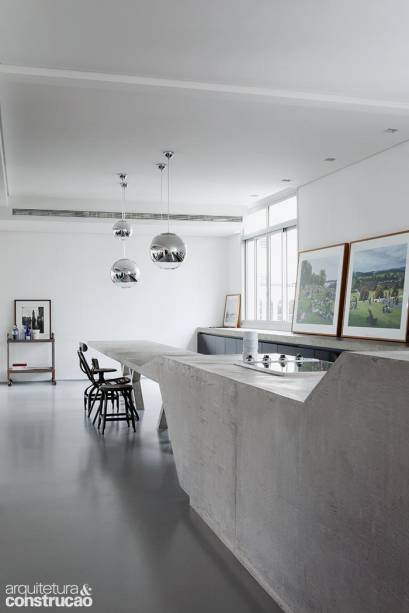 Inspirados na geometria do concretismo brasileiro, diversos volumes tomam os 520 m² desta cobertura paulistana, reformada pelo escritório Triptyque. É o caso do bloco que atravessa a cozinha aberta, delimitada pelo piso pintado de tinta epóxi. Sustentado por quatro pés em forma de X, ele começa como mesa de refeições (75 cm de altura) e segue como bancada para o cooktop (90 cm de altura). Moldado na obra, o concreto armado dispensou tratamento, mantendo a aparência original ao longo do apoio de 0,90 x 8,90 m.