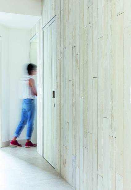 Para demarcar todo o bloco que corresponde à ala íntima deste apartamento, André Di Gregorio e Rodrigo Maçonilio, do Estúdio BRA Arquitetura, cobriram as paredes com ripas de concreto pigmentado (Tresuno), assim como as portas e os batentes, obtendo uma superfície única. Aplicadas com argamassa de assentamento, as faixas de 1,20 m de comprimento camuflam inteiramente as esquadrias, que não possuem maçanetas, mas puxadores cavados (10 x 10 cm).