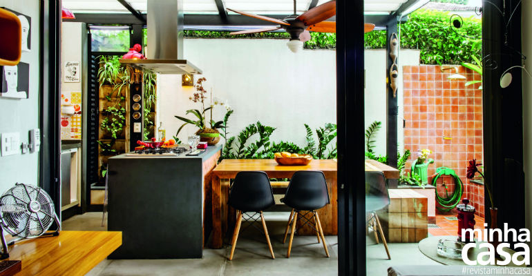Cozinha na varanda e jardim criam clima de casa em apartamento térreo