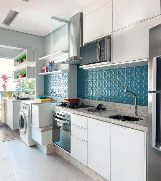 <span>Na cozinha, o destaque é a cerâmica em relevo junto à pia (Estrela Jeans Matte, 90 x 30 cm, da coleção Wall Color, da Portinari. Ibiza Acabamentos) – vistoso, o revestimento chama a atenção até de quem está na sala. </span><span>A divisória de vidro incolor separa cozinha e lavanderia sem criar obstáculos visuais. Projeto da designer de interiores Adriana Fontana.</span>