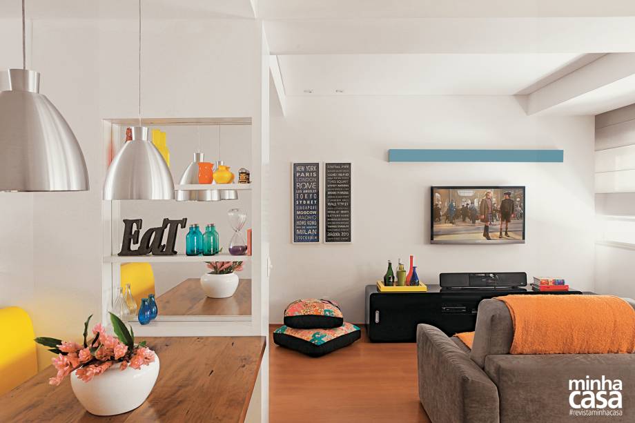 O espaço destinado ao home theater foi, há muitos anos, o terceiro quarto do apartamento – daí as vigas aparentes no teto e na parede da fachada. A integração havia sido feita pelo proprietário anterior. O sofá com assentos retráteis convida a se esparramar para assistir a filmes. “Ele tem presença e é muito confortável. Por isso, fizemos questão de tê-lo e de só completar o visual com almofadões”, conta Luciana. A elegante calha, laqueada de azul, promove uma iluminação suave logo acima da TV, fixada na parede. O rack preto de estilo retrô, com cantos levemente arredondados, revela o traço das arquitetas. Apesar das paredes brancas, há cor por toda parte: nas almofadas, na manta do sofá, nas obras de arte e nos objetos que pontuam a decoração. Projeto das arquitetas Isabella Lucena e Joanna Fraga.