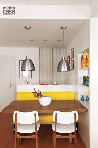 Larga e ripada, a porta entre a sala e a cozinha parece um painel decorativo. Quando abertas, suas folhas ficam ocultas na alvenaria. iluminação sobre a mesa leva dois pendentes de alumínio, que emprestam um ar descontraído ao espaço. Projeto das arquitetas Isabella Lucena e Joanna Fraga.
