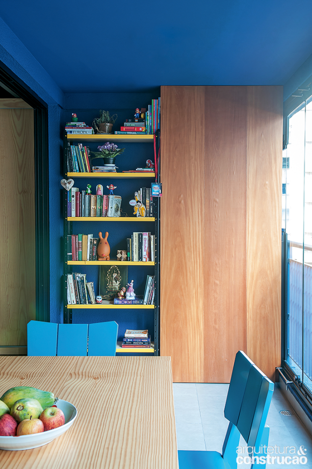 Do outro lado, o espaço se divide entre minibiblioteca e uma área técnica para o ar-condicionado, guardado atrás da porta de garapeira.
