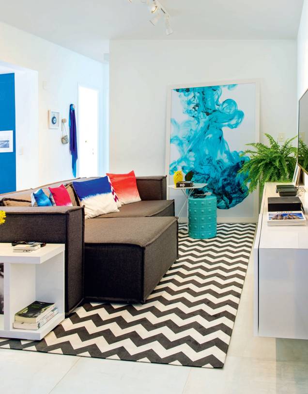 <span>“O predomínio de linhas retas e cores neutras no mobiliário torna mais fácil encaixar outros tons e formas”, explica o arquiteto. Exemplo disso é o modo como o sofá cinza compõe com itens como as almofadas coloridas e o tapete estampado (Chevron 56, 1,80 x 3,20 m, base de veludo. Tamtum). Projeto do arquiteto Lucas de Paula.</span> <span>“O predomínio de linhas retas e cores neutras no mobiliário torna mais fácil encaixar outros tons e formas”, explica o arquiteto. Exemplo disso é o modo como o sofá cinza compõe com itens como as almofadas coloridas e o tapete estampado (Chevron 56, 1,80 x 3,20 m, base de veludo. Tamtum). Projeto do arquiteto Lucas de Paula.</span>
