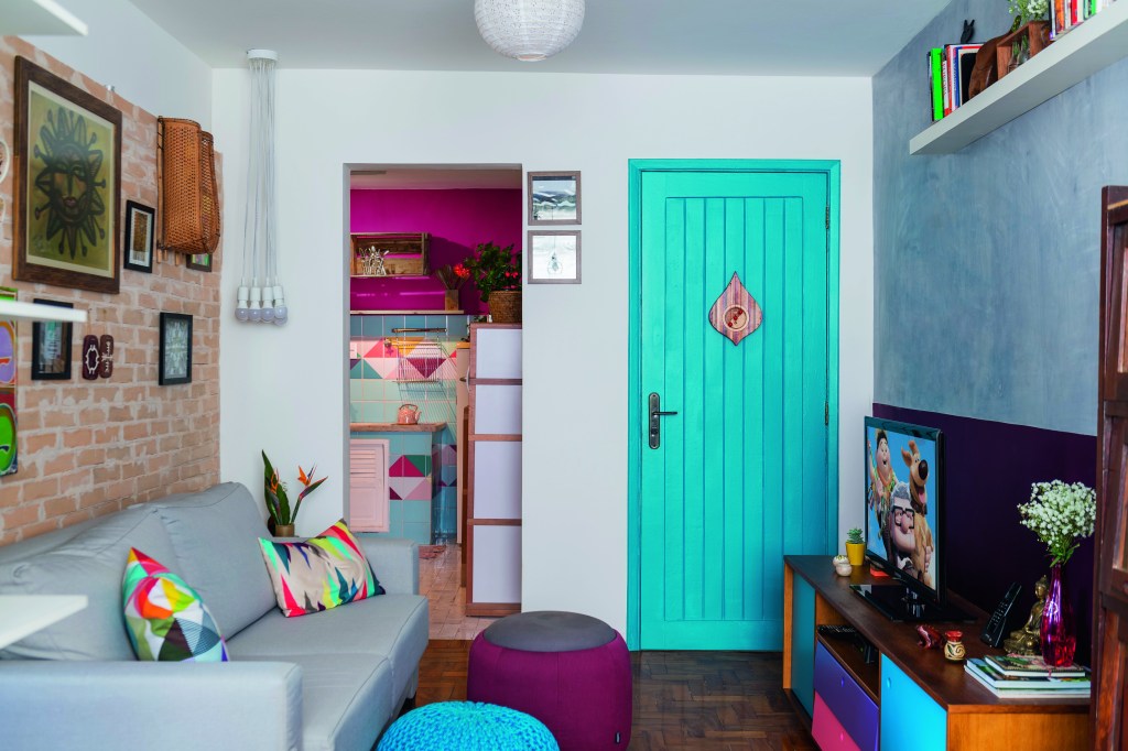Sala de estar de uma pequena residência, colorida com detalhes em diversas cores.