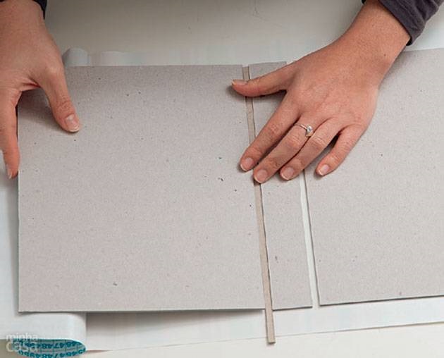 3. Use o filete de 0,5 cm de papel holler apenas como um gabarito para estabelecer as distâncias entre a parte já colada e o recorte de 3,5 x 27 cm (que será a lombada) e entre ele e a outra parte de 20,5 x 27 cm. Fixe tudo.