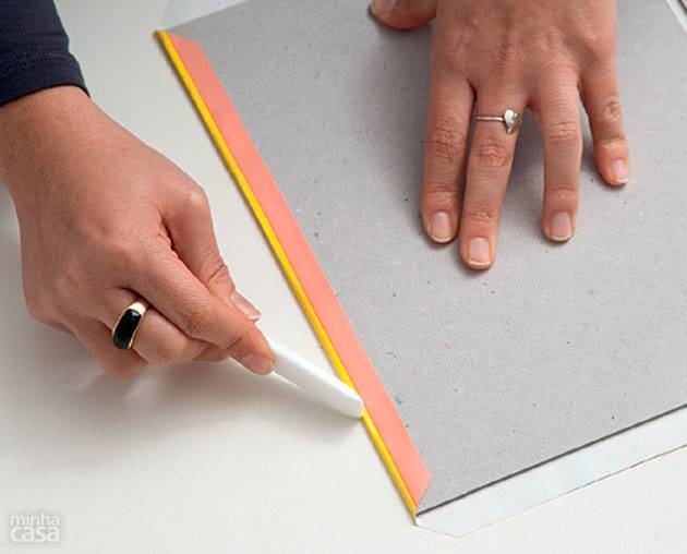 5. Com a ajuda da dobradeira, vire a borda do adesivo para dentro, vincando-o bem sobre o papel holler.