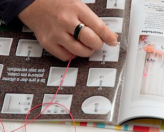 12. Comece a costurar a revista na capa dura - nesse momento, você usará apenas os três furos da primeira linha vertical do gabarito A. Atravesse o fio encerado pelo furo do meio, na revista e, depois, na capa, deixando 15 cm do lado de dentro.