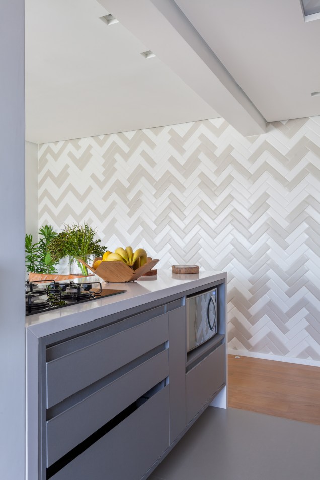 Repare que o painel de azulejos (PortobelloShop) paginado no formato espinha de peixe ocupa também uma parede entre a sala e a cozinha.