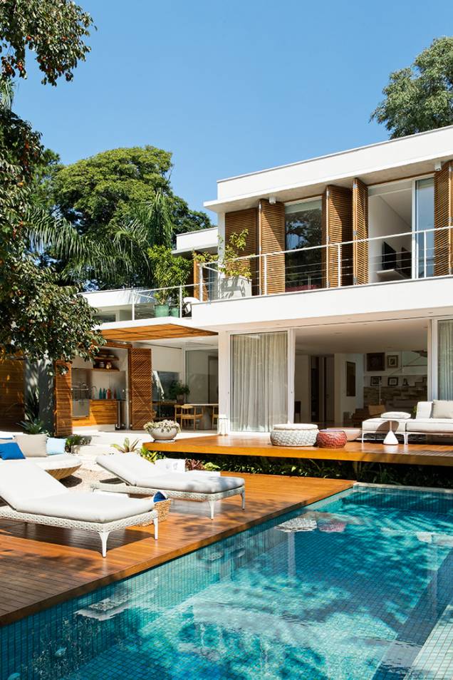 Nos fundos da casa, o lounge da churrasqueira, a sala de jantar e a de estar se unem ao jardim e à piscina, voltada para nordeste (que recebe os saudáveis raios da manhã). Os três quartos do pavimento superior também se direcionam para cá – portas de correr do tipo camarão resguardam o interior do sol. Nos fundos da casa, o lounge da churrasqueira, a sala de jantar e a de estar se unem ao jardim e à piscina, voltada para nordeste (que recebe os saudáveis raios da manhã). Os três quartos do pavimento superior também se direcionam para cá – portas de correr do tipo camarão resguardam o interior do sol.
