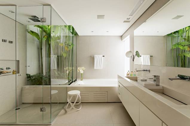 O jardim interno, aberto no teto e com vidro só nas laterais, fornece ventilação e luz natural (o vidro fixo jateado, à dir. da banheira, também ajuda a clarear o espaço). Porcelanato cinza (Portobello) em piso e paredes. Na bancada e ao redor da hidromassagem, mármore Sivec. O jardim interno, aberto no teto e com vidro só nas laterais, fornece ventilação e luz natural (o vidro fixo jateado, à dir. da banheira, também ajuda a clarear o espaço). Porcelanato cinza (Portobello) em piso e paredes. Na bancada e ao redor da hidromassagem, mármore Sivec.