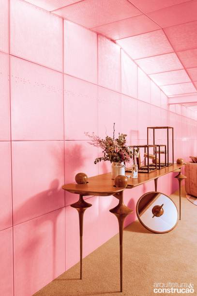 Tetos em destaque: chapas de alumínio perfuradas e pintadas num tom rosa-acobreado revestem as paredes e delineiam o forro do projeto idealizado por Leo Romano. A textura faz um convite à experimentação: pontos aplicados nas laterais do ambiente revelam mensagens em braile.