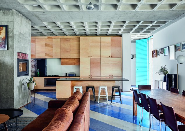 Jantar e cozinha unidos compartilham o mesmo – e prático – piso vinílico, que alterna faixas entre o azul e o cinza.