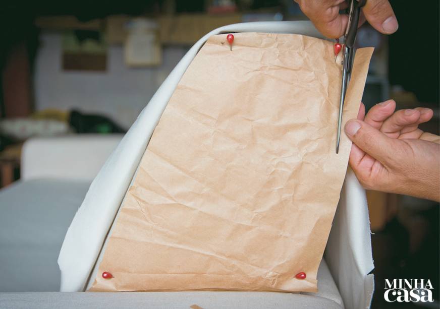 4. Um molde ajuda nas áreas irregulares: alfinete um pedaço de papel kraft no estofado e corte rente à peça. Use esse modelo para cortar o tecido.
