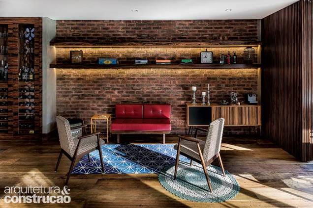 O primeiro ambiente do térreo é esta pequena sala, integrada à maior. Tijolinhos ingleses (Palimanan) na parede e madeira pau-ferro (aplicada no bar, prateleiras e porta de correr) aquecem o espaço com os móveis vintage garimpados pelo casal. Poltronas da Maria Jovem. O primeiro ambiente do térreo é esta pequena sala, integrada à maior. Tijolinhos ingleses (Palimanan) na parede e madeira pau-ferro (aplicada no bar, prateleiras e porta de correr) aquecem o espaço com os móveis vintage garimpados pelo casal. Poltronas da Maria Jovem.
