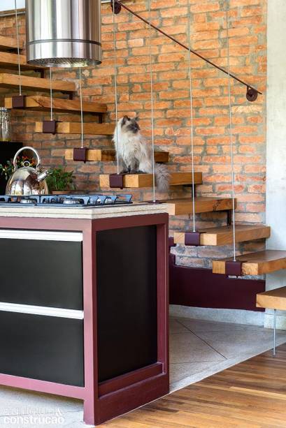 Cabos de aço sustentam as sobras de madeira que dão forma à escada em que posa Zé Batata, o gato do casal.