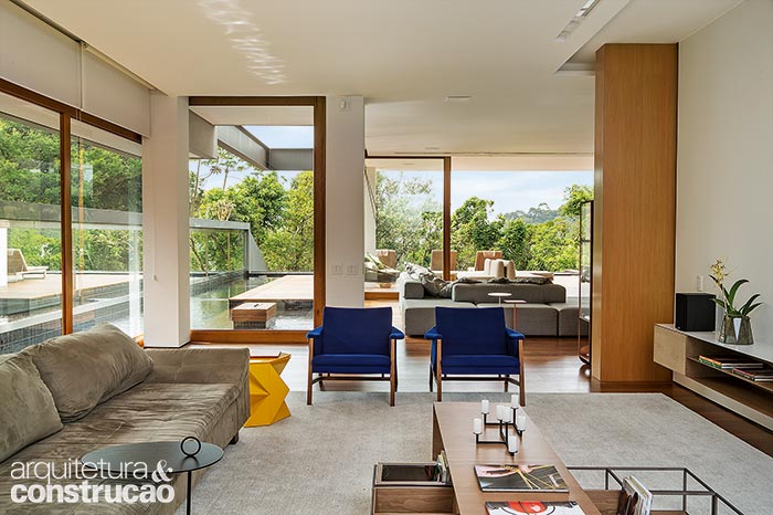 Lá fora, a lateral espelhada reflete a paisagem e causa a impressão de que a construção é mais ampla. Na sala de TV, piso de ipê. Lá fora, a lateral espelhada reflete a paisagem e causa a impressão de que a construção é mais ampla. Na sala de TV, piso de ipê.