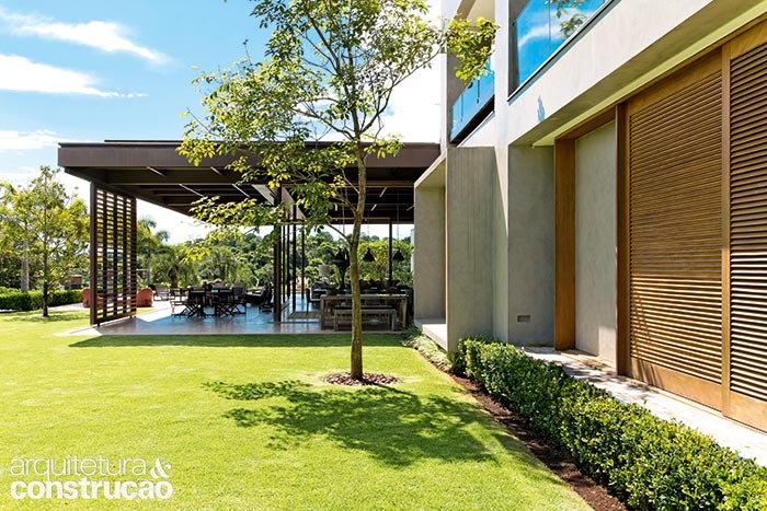 Quando todos os caixilhos são recolhidos, a área social vira um grande terraço. Com estrutura de concreto, o bloco de dois andares dos quartos conta com janelas do piso ao teto, que aparecem organizadas e protegidas por caixas esculpidas na fachada.
