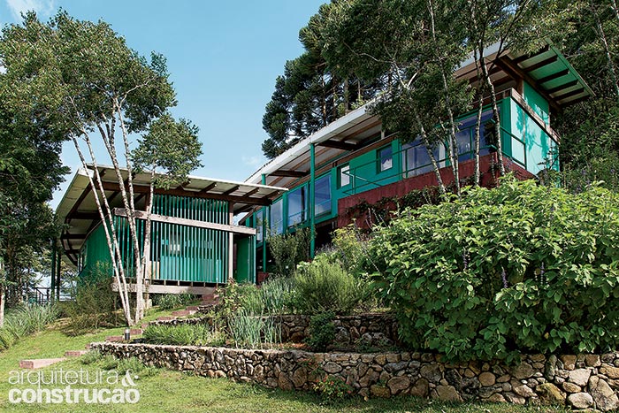 Esta foto desvenda o posicionamento dos dois pavilhões, escalonados no declive. No de cima, a suíte principal se situa na ponta da direita, com vista totalmente liberada para o vale. Os outros quartos enxergam a paisagem também através dos painéis de vidro da sala, na construção inferior.