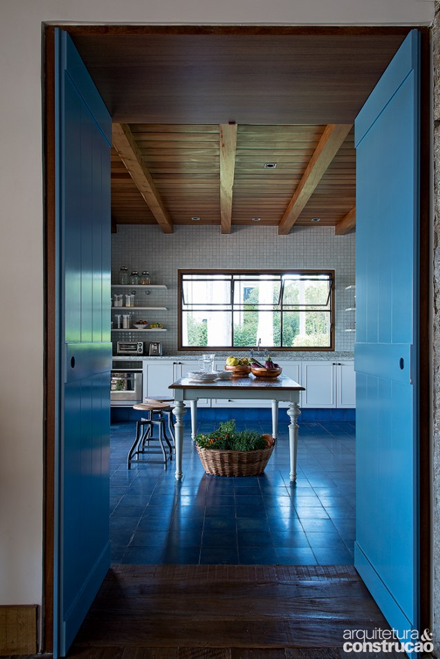 O azul (Suvinil, ref. D076) da porta de madeira surge também no piso de ladrilhos hidráulicos da cozinha (Dalle Piagge, ref. Azul Ultramar). Na parede, pastilhas da Jatobá. Mesa da Secrets de Famille.
