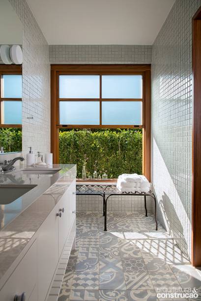 Tons de azul também surgem no piso do banheiro, que tem patchwork de nove estampas diferentes de ladrilho hidráulico (Dalle Piagge). Pastilhas da Jatobá nas paredes e bancada de Silestone. Banco da Secrets de Famille.