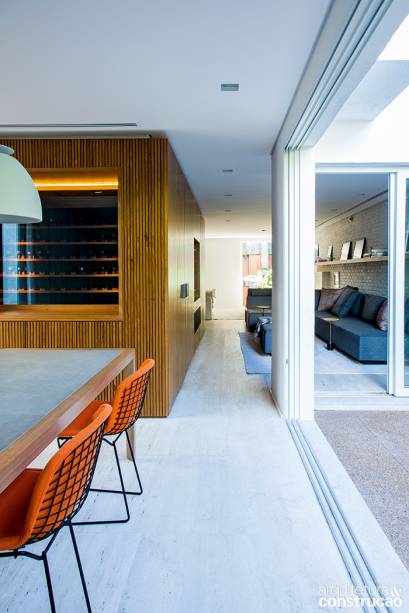 A caixa de freijó oculta a passagem para o segundo andar e assume outras funções: é painel para embutir a TV, aparador para a sala de jantar e vitrine para a adega do morador. A caixa de freijó oculta a passagem para o segundo andar e assume outras funções: é painel para embutir a TV, aparador para a sala de jantar e vitrine para a adega do morador.