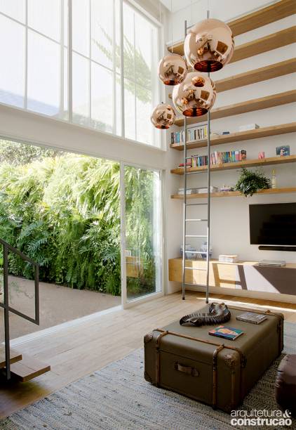 Redesenhada, a edícula ganhou um trecho com pé-direito duplo, perfeito para dar lugar à biblioteca. No mezanino, o morador acomodou uma miniacademia, que frequenta assiduamente. Lá fora, o jardim com piso de fulgê é espaço concorrido – o favorito de Asterix, o border collie.