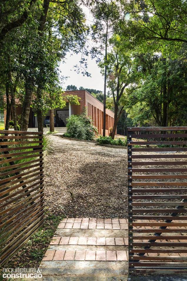 Da porteira vê-se a casa, implantada numa clareira existente. O acesso de carros e as trilhas para caminhada contornam as árvores, mapeadas e preservadas. Da porteira vê-se a casa, implantada numa clareira existente. O acesso de carros e as trilhas para caminhada contornam as árvores, mapeadas e preservadas.