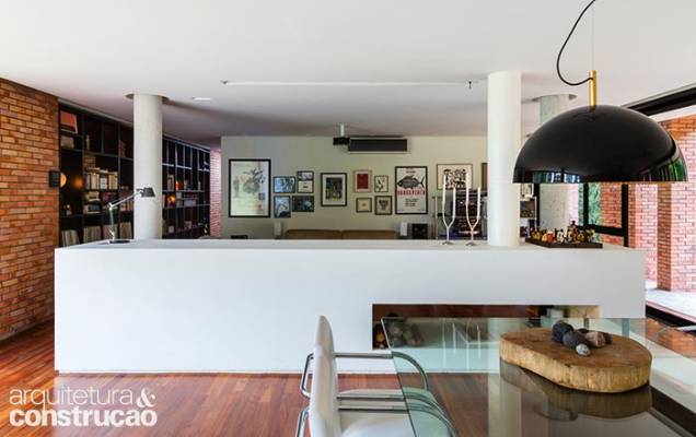 Dois blocos de tamanhos iguais setorizam a área social sem dividi-la: a ilha da cozinha e a lareira, feita de alvenaria, com emboço e pintura. Dois blocos de tamanhos iguais setorizam a área social sem dividi-la: a ilha da cozinha e a lareira, feita de alvenaria, com emboço e pintura.