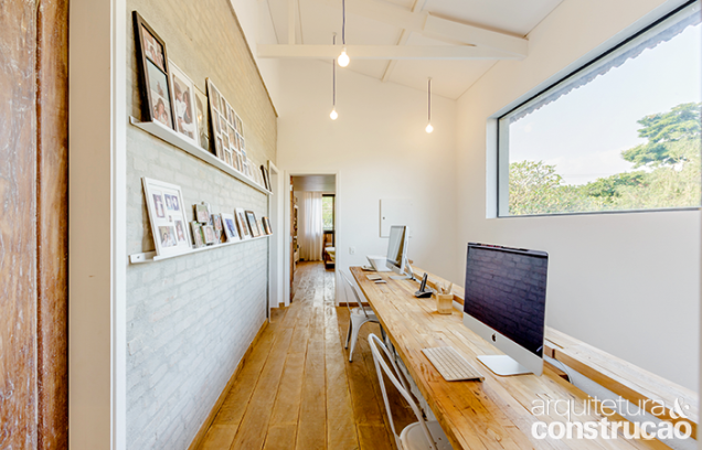 Instalado no corredor do piso de cima, o home office recebe muita claridade e a iluminação de pendentes simples e econômicos.