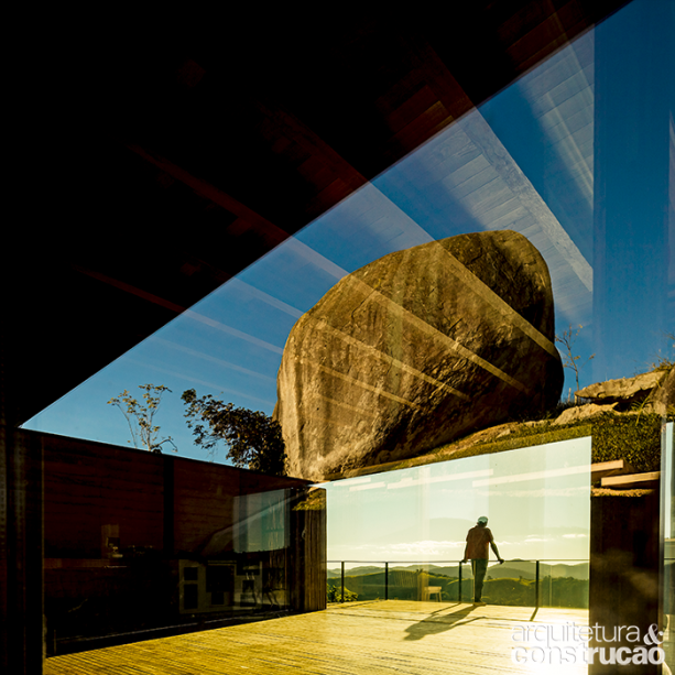 Ilusão de ótica: tirada no lado sul da casa, esta foto mostra a pedra do terreno refletida no próprio vidro da fachada. Ao fundo, o deck da vista ao norte.