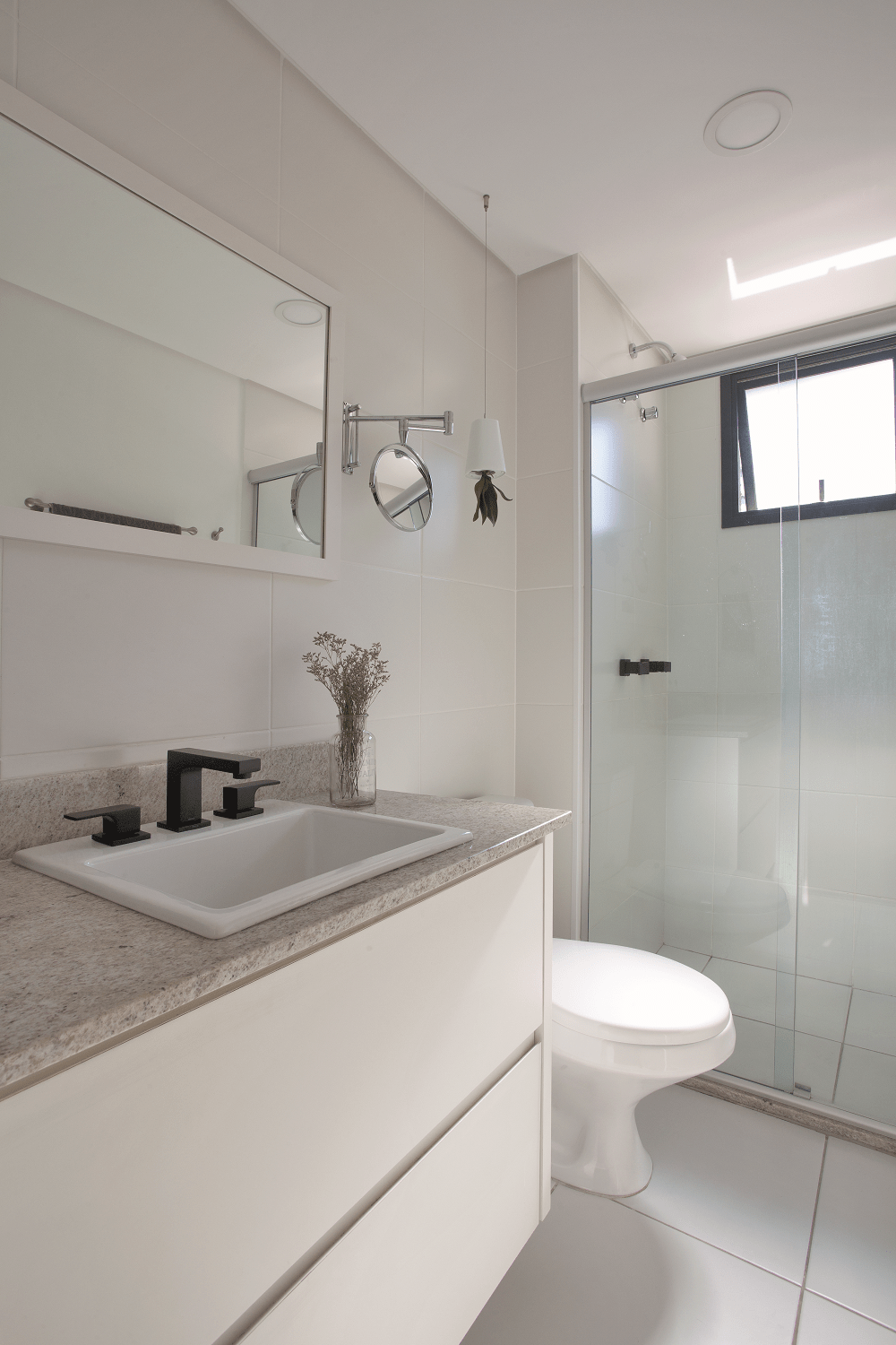 Banheiro pequeno branco com bancada de granito e armário branco.