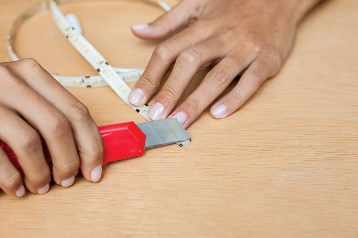 2. LIBERE O CONTATO | Alguns modelos de fita são cobertos na frente por uma camada de epóxi ou silicone, que dificulta a união das peças. Com o auxílio de um estilete, tire essa proteção e deixe a parte metálica acessível para uso do plugue conector (ou vampirinho), vendido à parte.
