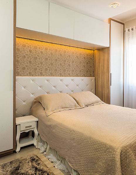 <span>Vedete do ambiente, a cabeceira estofada foi valorizada com &nbsp;ilumina&ccedil;&atilde;o indireta. Para tanto, bastou usar uma fita de LED estrategicamente acoplada no m&oacute;vel a&eacute;reo. O papel de parede floral arremata a composi&ccedil;&atilde;o. Projeto da arquiteta&nbsp;Camila Chalon.</span>
