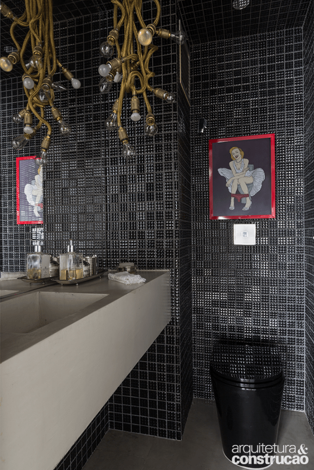 Tons escuros são predominantes no banheiro que traz elementos divertidos como a ilustração emoldurada sobre a bacia sanitária Tons escuros são predominantes no banheiro que traz elementos divertidos como a ilustração emoldurada sobre a bacia sanitária