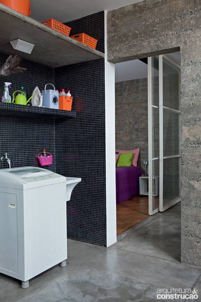 Para manter a unidade do apartamento, o piso de cimento aplicado em requadros de 1 m² estendeu-se à área de serviço. Também aqui, parte das paredes teve a massa retirada e, como nas alas íntimas, assumiu o aspecto brutalista do concreto aparente. A área reservada aos equipamentos foi revestida com as mesmas pastilhas pretas do novo balcão.