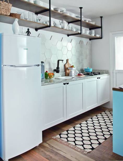 <span>O projeto da cozinha americana de onze metros quadrados surpreende ao exibir elementos mais clássicos, como os gabinetes brancos e os azulejos hexagonais, juntamente com soluções moderninhas, como a estante feita com canos de PVC e a composição de cadeiras diferentes. Projeto das arquitetas Fabiana Silveira e Patricia de Palma, sócias do SP Estudio.</span>