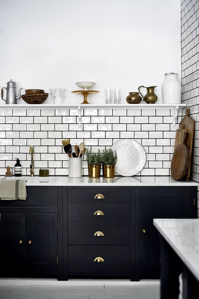 Cozinha com bancada preta e parede de tijolinhos brancos