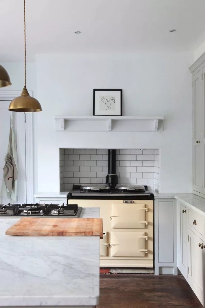 Cozinha com armários brancos e nicho revestido de tijolinhos