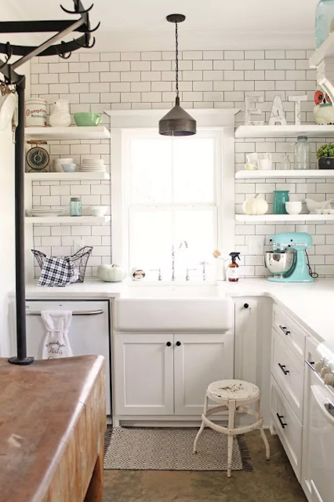 Cozinha branca com armários e prateleiras brancas. Tijolinhos brancos